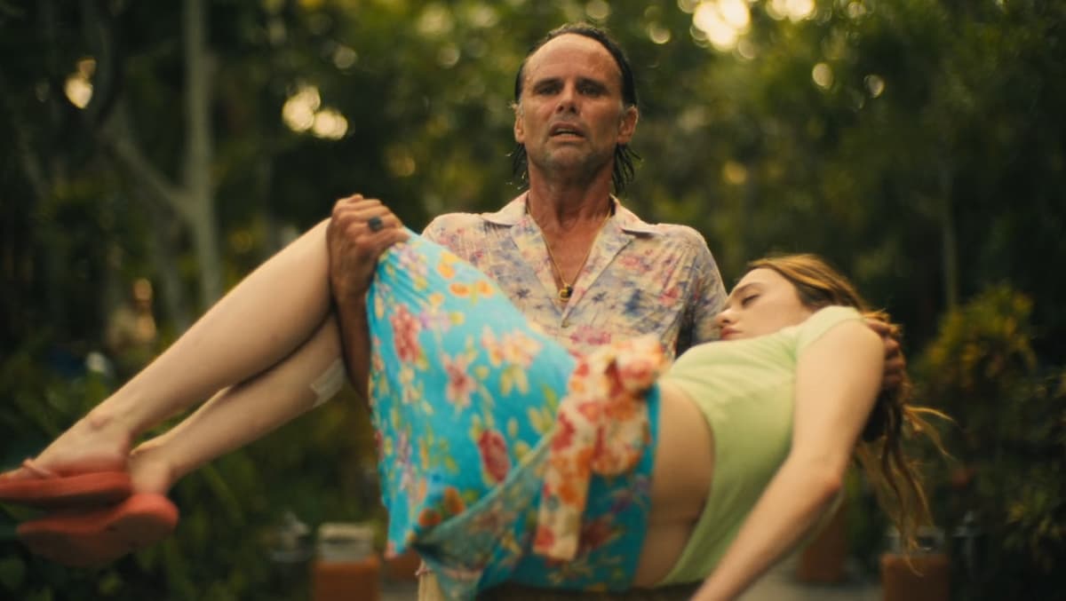 a man carrying a dead woman in his arms in white lotus season 3